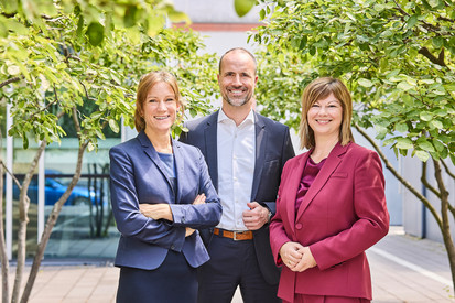 Porträtfotos mit Gesundheitsminister Clemens Hoch, Staatssekretärin Nicole Steingaß und Ministerialdirektorin Katharina Heil draußen unter Bäumen.